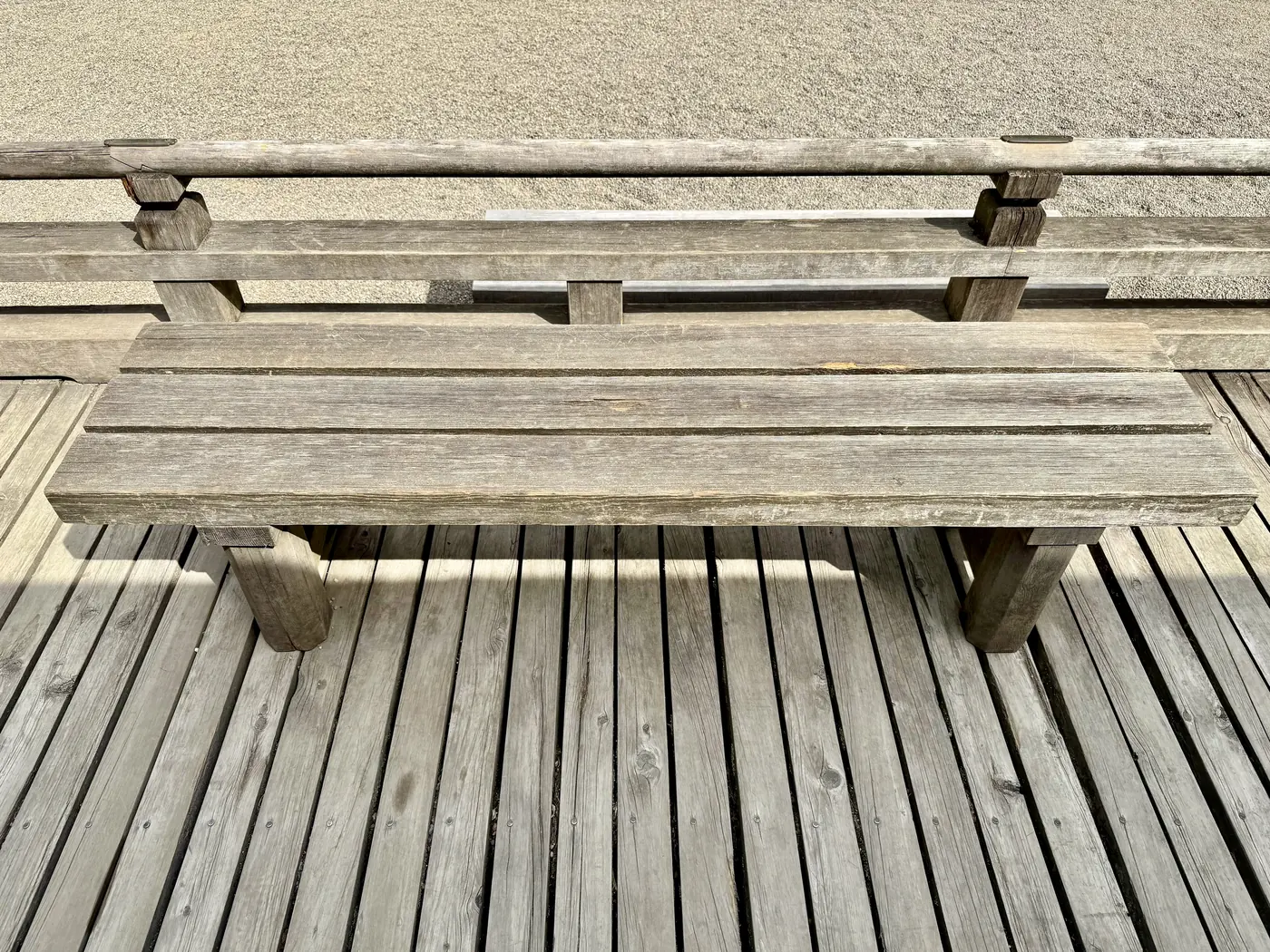 Silvered grey deck boards and a weathered bench, shot from directly above.