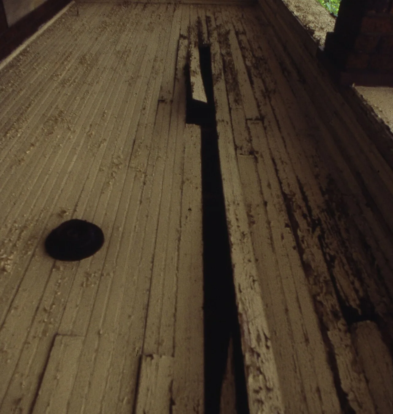 Weathered deck boards with a wide split running the length of one plank.