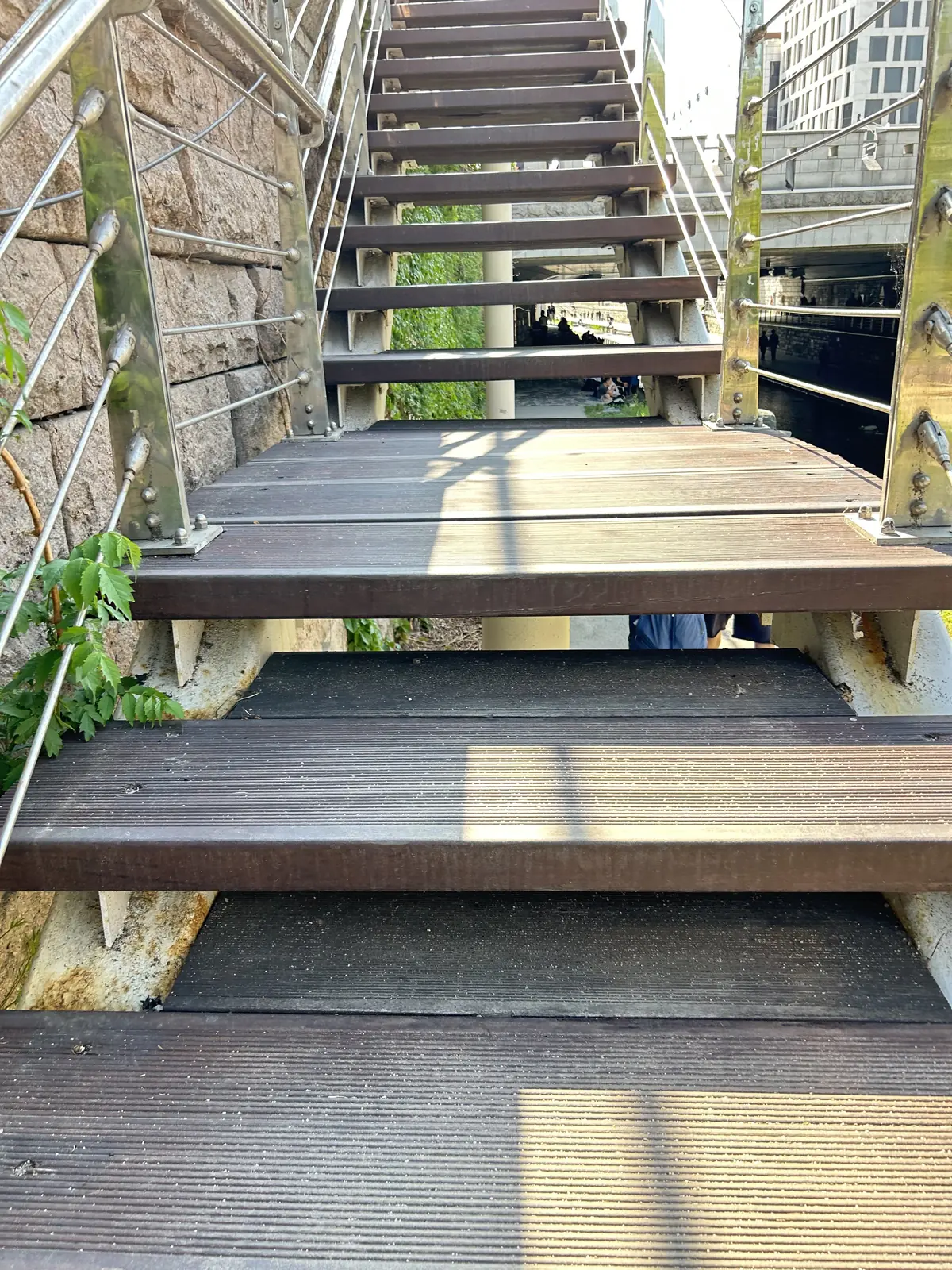 Dark stair treads with a steel and cable handrail running up beside them.